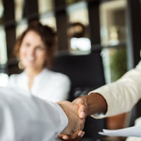 two people shaking hands across a table
